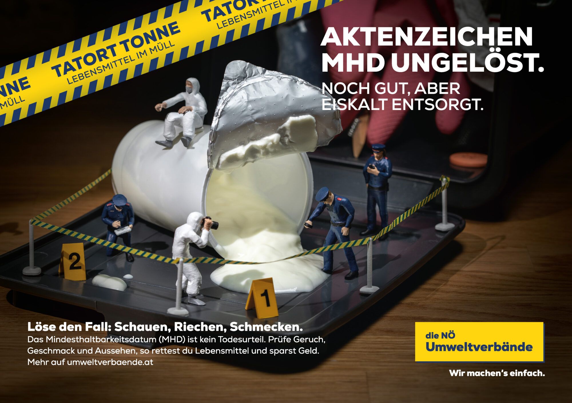 Miniaturpolizisten inspizieren den Tatort Tonne voll Joghurt.