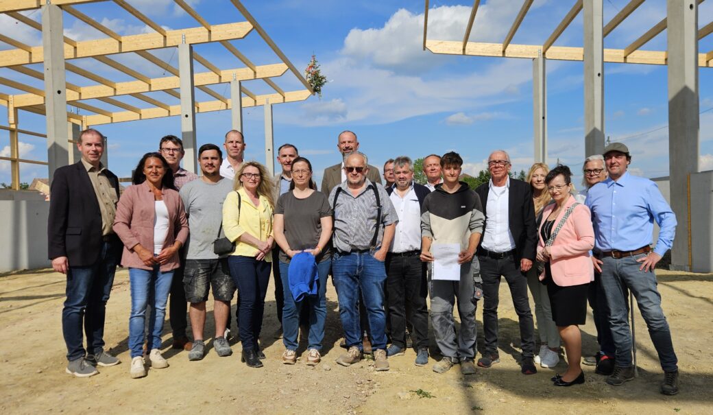 Am Gruppenbild, das auf der Baustelle des WSZ aufgenommen wurde, zeigt ein Gruppenbild von Bürgermeisterinnen und Bürgermeistern, Vertretern der Baufirmen, Gemeinderäte und des GAUL. Im Hintergrund ist auf dem Dachstuhl ein Gleichenbaum zu sehen.
